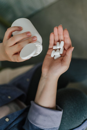 White pills on hand and pill bottle, top view. Healthcare, medication, or self-care concept.