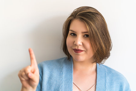 Plus-size woman making warning gesture with index finger, expressing caution and attention. Advice,...