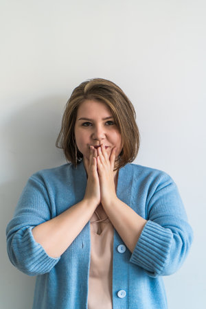 Thoughtful plus size woman with hands covering her mouth, vertical image.
