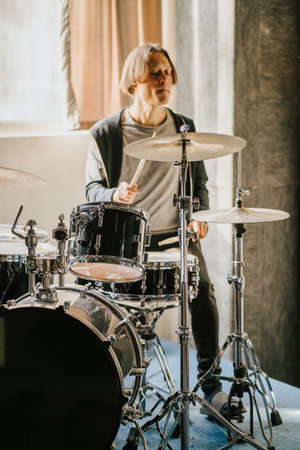 Drummer playing drum set in recording studio. Focused musician performing on drums, surrounded by professional equipment, vertical imageの写真素材
