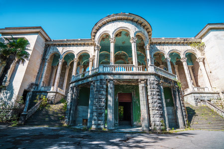 Facade of abandoned Medea sanatorium in Tskaltubo, Georgia. Neoclassical architecture with tall columns and grand arches shows signs of decay, surrounded by nature.の写真素材