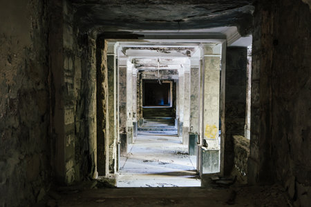 Dark, decaying hallway in abandoned building, crumbling walls and debris scattered on floor.の写真素材