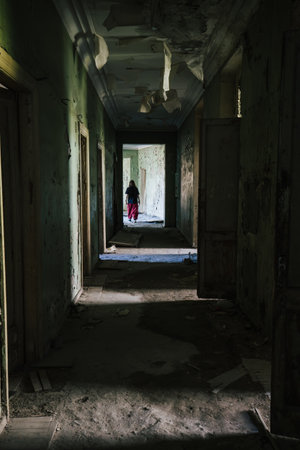 Dark, decaying hallway in abandoned building and silhouette of person, vertical imageの写真素材