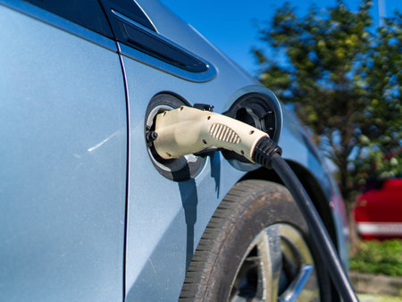 Electric car charging plug for ecofriendly transport, showing sustainable mobility trend and clean energy future in outdoor parking area.の写真素材