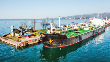 LPG tanker ship docked at industrial terminal for gas loading or unloading in sunny weather,...
