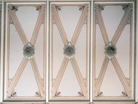 Ornate ceiling panel with symmetrical neoclassical design, featuring intricate patterns, decorative moldings, and beige-toned geometric elements. Elegant architectural detail with vintage aesthetic.の写真素材