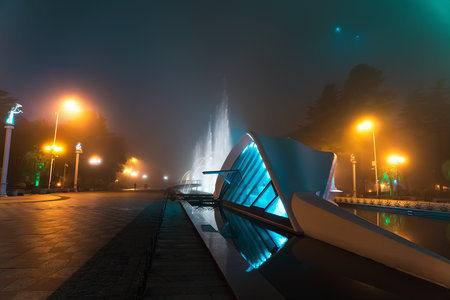 Foggy evening in Batumi and illuminated fountain with glowing lights.の写真素材