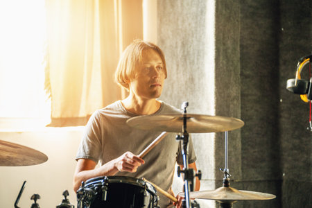 Drummer sitting at drum kit in recording studio, artistic portrait, creative inspiration, musician lifestyle, music session, indoor atmosphere.の写真素材