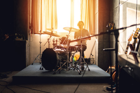 Drummer play in music studio, rehearsal session with warm sunlight, band practice, indie rock vibe, sound production, creativity.の写真素材