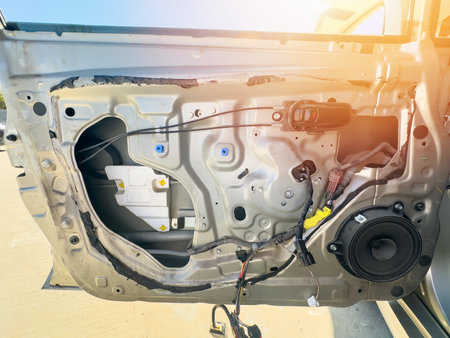 Car door without panel closeup showing inner mechanism, wiring, speaker, and handle. Useful for auto repair, electronics, DIY tutorials, mechanical education, car maintenance, engineering content.の写真素材