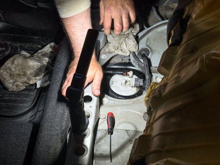 Mechanic checking automotive fuel system under rear seat, diagnostic tools and hands visible, professional car repair service and maintenance.の写真素材
