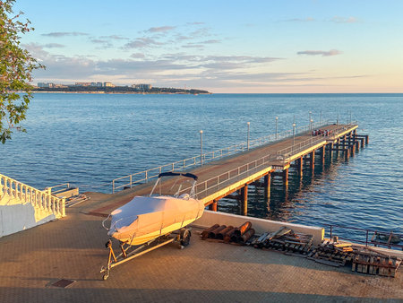 Boat docked near pier at golden hour, with calm sea and sunset reflections, ideal for travel, marine transport and coastal infrastructure themesの写真素材