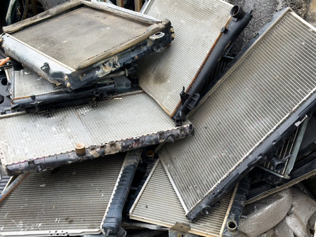 Old used car radiators stacked in scrapyard, automotive waste recycling, vehicle parts disposal, metal salvage, damaged cooling systems, industrial junk and spare parts.の写真素材
