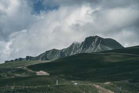 Dramatic mountain landscape with rocky peaks and cloudy sky, remote green valley, nature wilderness, hiking destination, adventure background.の写真素材
