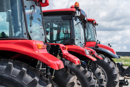 Red tractors parked in row at dealership or farm show. Agriculture, farming equipment, industrial transport and machinery.の写真素材