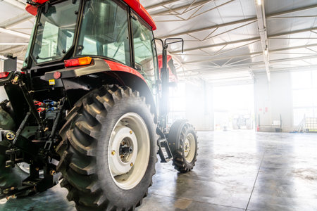 Tractor inside agricultural machinery factory warehouse workshop service center for farming industry, agrotechnology, transport logistics.の写真素材