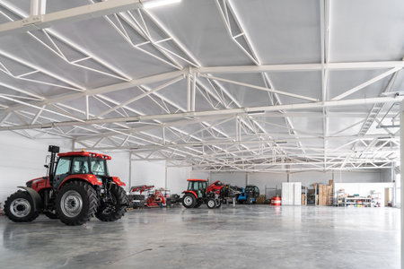 Modern agricultural warehouse with red tractors and farming equipment storage space.の写真素材