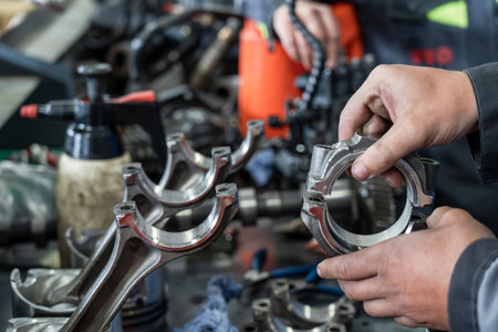 Automotive technician inspecting connecting rod at car workshop, detailed view of engine components,...