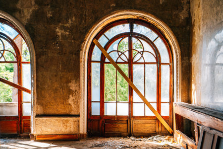 Arched wooden window in abandoned historic building, aged wall texture and natural sunlight through frosted glass, vintage decay architecture.の写真素材