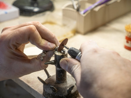 Dental technician polishing metal framework of dental bridge in laboratory prosthodontic production...