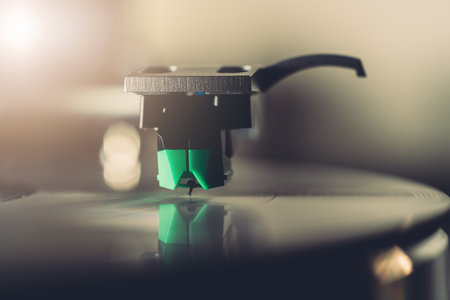 Stylus needle playing vinyl record on turntable close up. Retro analog music equipment with soft ambient lighting. Nostalgia, vintage audio, and timeless sound experience concept.の写真素材