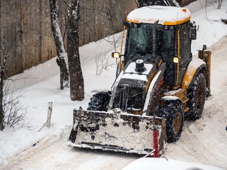 Snow-covered tractor lifting fresh snow during winter storm cleanup.