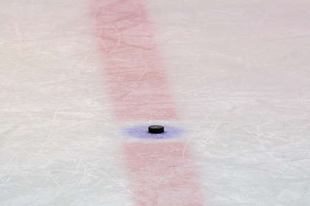 Hockey puck on ice stadium on the red lineの写真素材