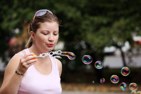 Young woman blows bubbles in a city parkの写真素材