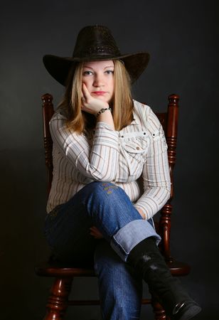Cowgirl in a jeans sitting on a chair の写真素材