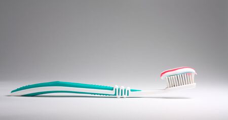 Colored toothpaste at a toothbrush at light backgroundの写真素材