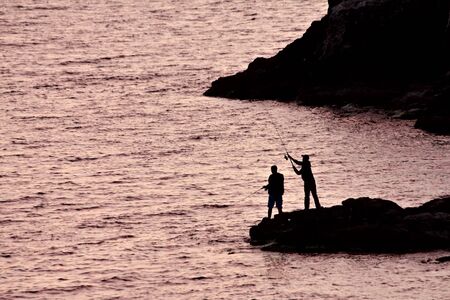Two men fishing from the shoreの写真素材