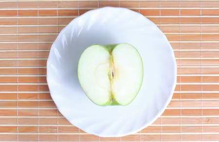 Half of apple on the plate at textured backgroundの写真素材