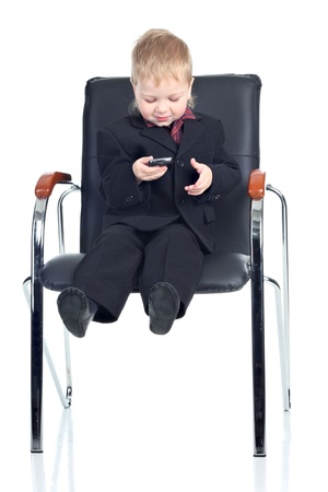 Little businessman with a phone on a chairの写真素材