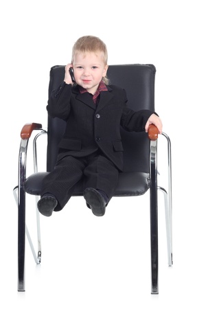 Little businessman with a phone on a chairの写真素材