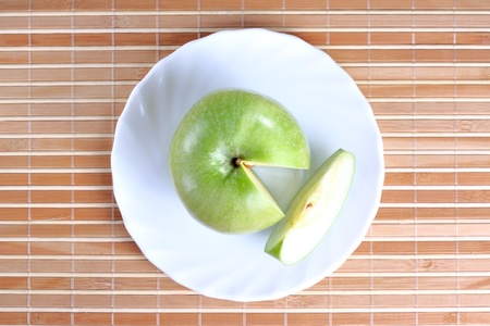 Apple with a piece on the plate at the textured backgroundの写真素材