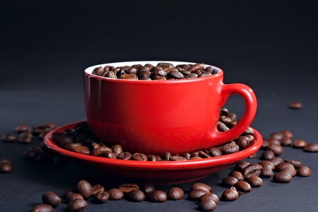 Cup on the saucer with coffee beans at the dark backgroundの写真素材