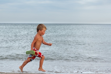 Little boy running at the shore near the seaの写真素材