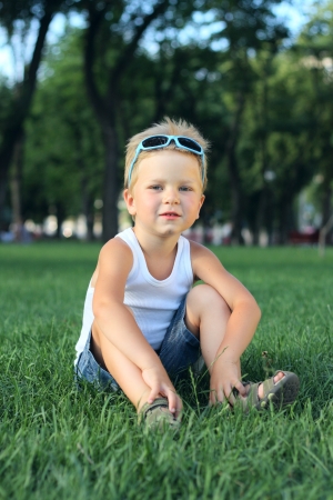 Little boy sitting in the park on a grassの写真素材
