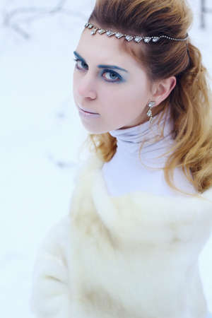 Portrait of young beautiful girl among a snowの写真素材