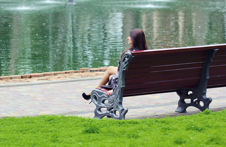 Woman sitting near the river at the benchの写真素材