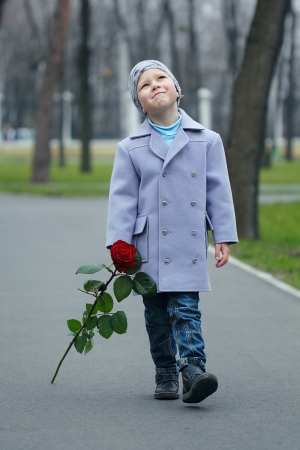 Little romantic boy with rose walking in the parkの写真素材