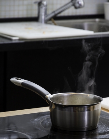 Little saucepan with boiling water on the plateの写真素材