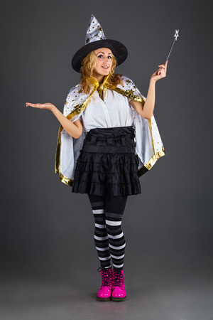 Young witch with magic wand at grey backgroundの写真素材
