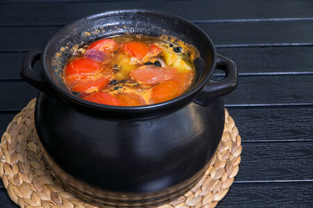 Soup in the black saucepan at wooden tableの写真素材