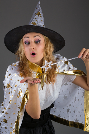 Young witch with magic wand at grey backgroundの写真素材