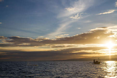 Dark boats in the yellow and blue sunset, the ocean and the silhouettes of the mountains
