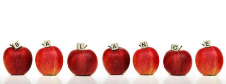 a row of red apples with cubes of letters on it in front of a white background - balance
