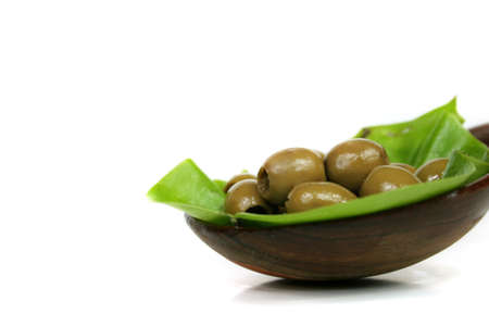 A few olives in a bowl of lumber on a green leafの写真素材