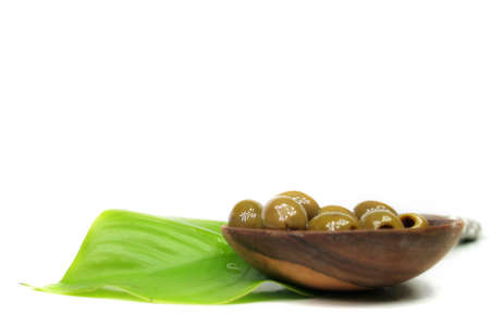 A few olives in a bowl of lumber on a green leafの写真素材