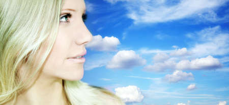 Portrait of Fresh and Beautiful blond woman in front of the blue sky with cloudsの写真素材